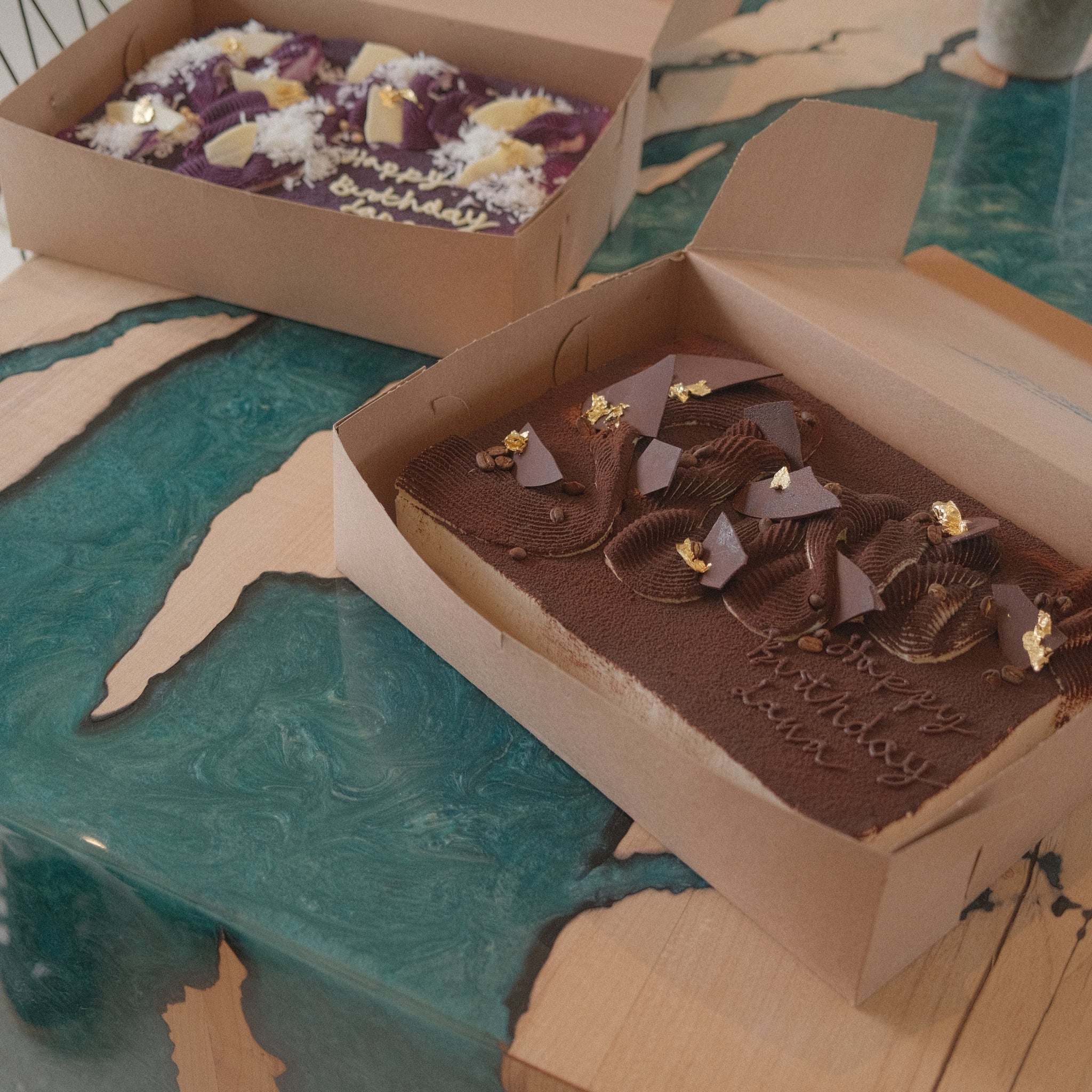 Two whole rectangular genoise cakes on a kitchen island with blue resin design. 