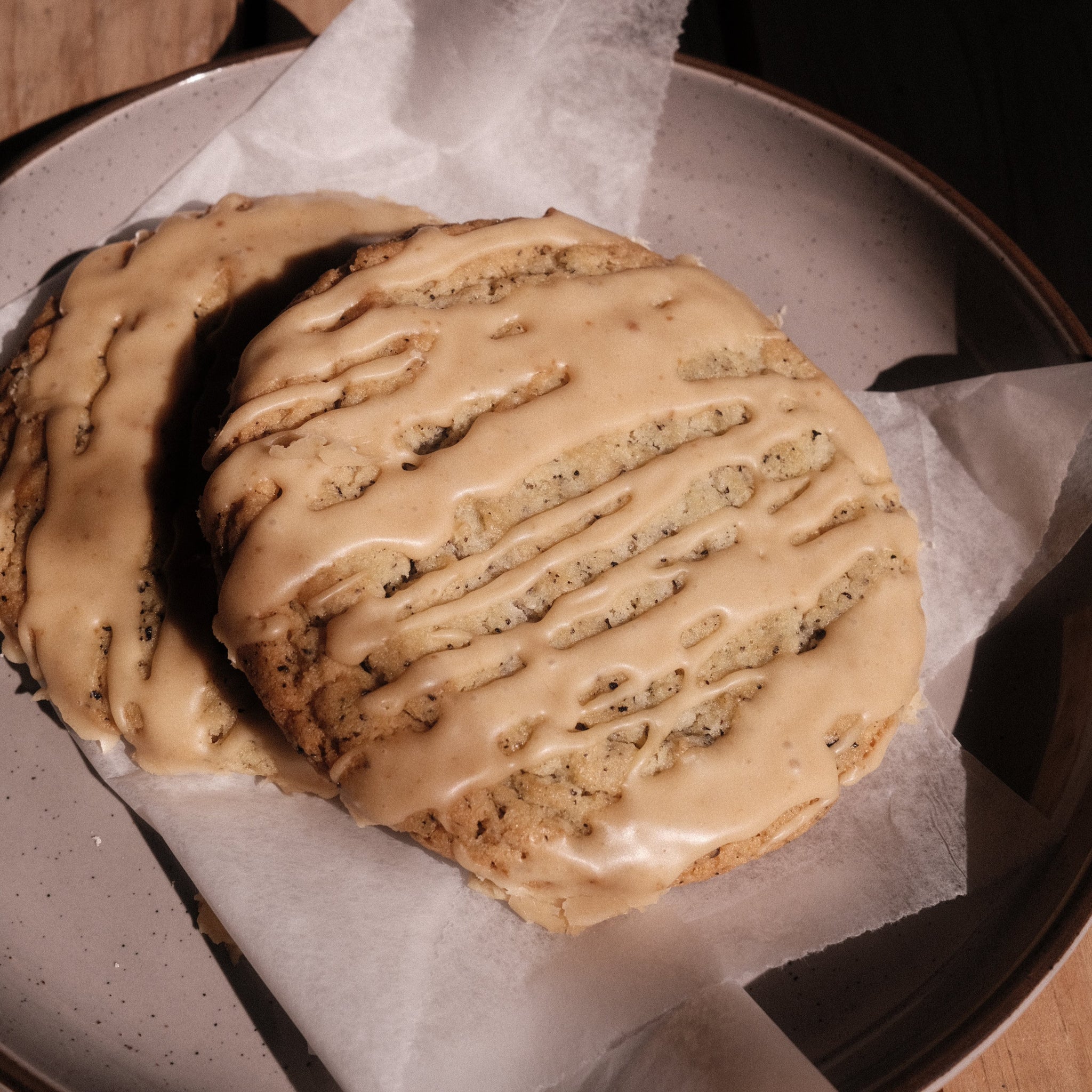 Earl grey yuzu cookie with striping of yuzu icing on a grey plate.