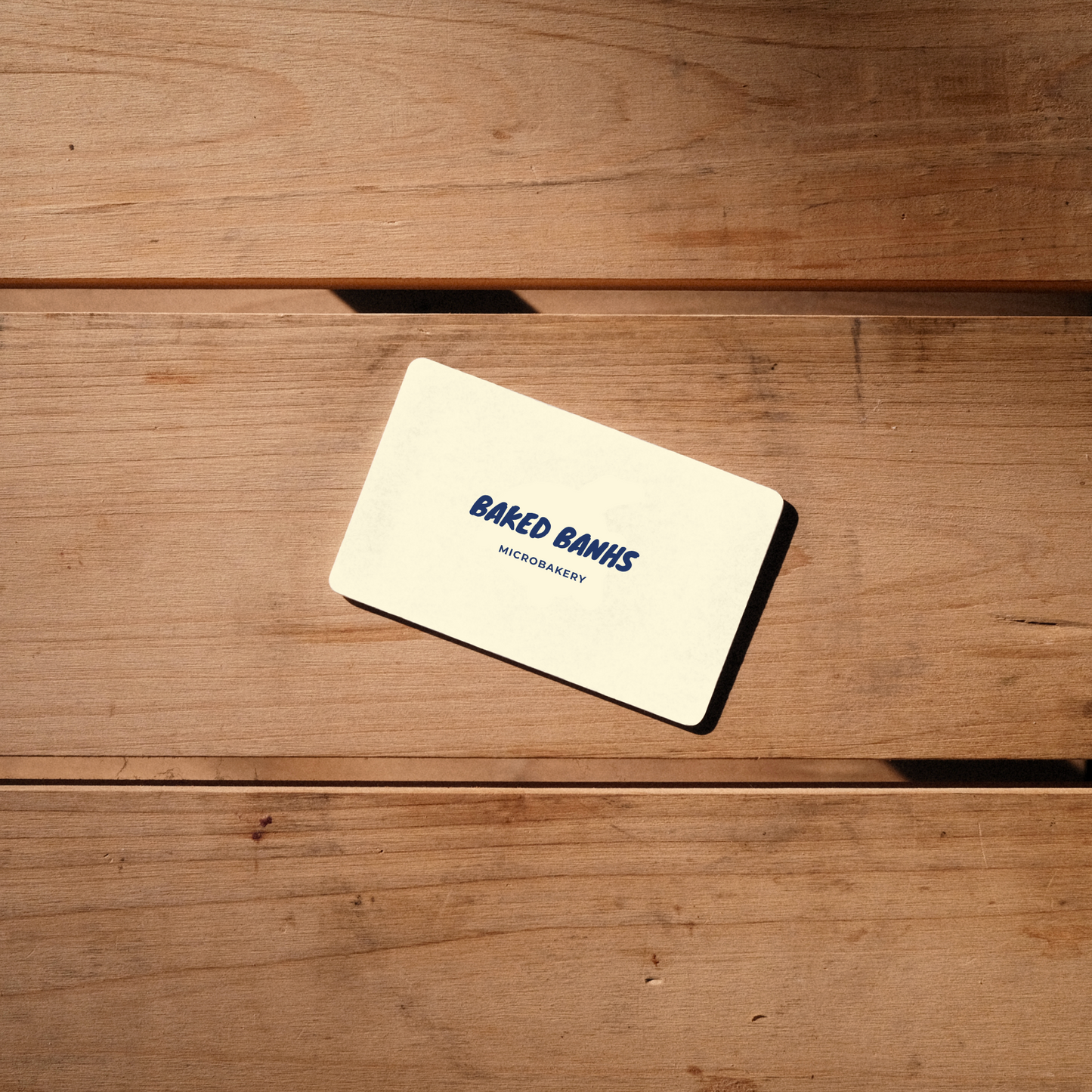 A top down view of a Baked Banhs Gift Card on a wooden table